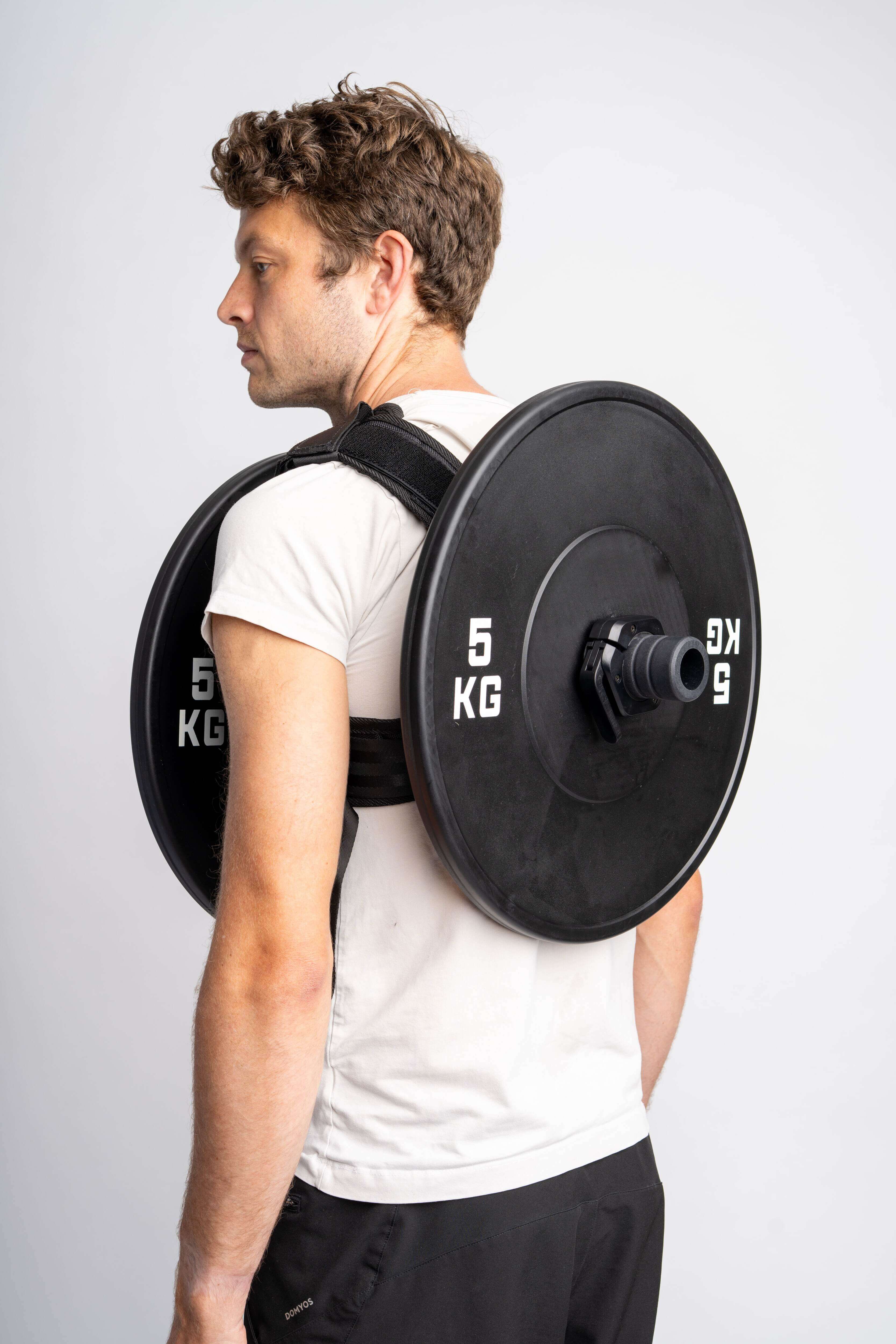 Man wearing a 5 kg weight plate on a removable weight vest, ideal for full-body workouts and strength training.